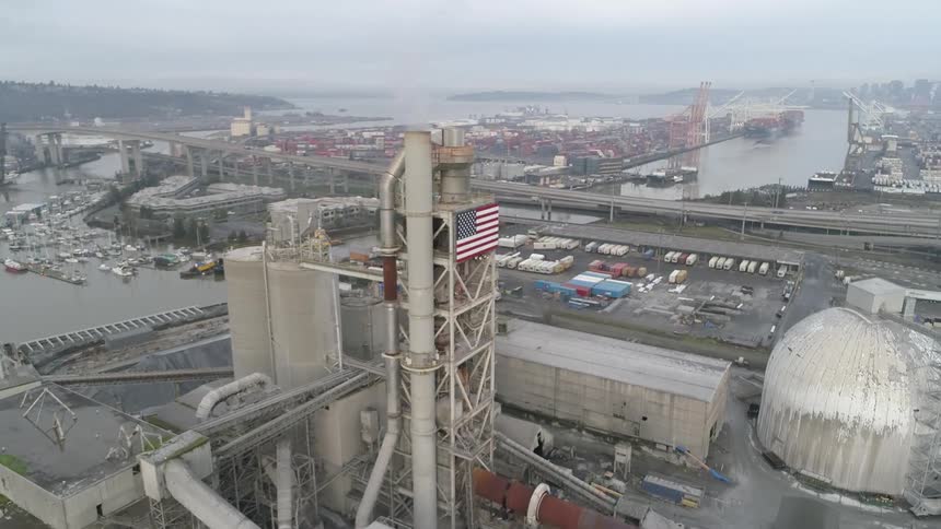 Aerial shot of a seaside factory with a city in the background