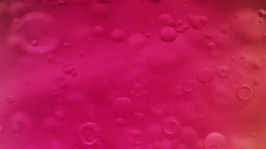 Pink liquid bubbles suspended in fluid create an abstract texture