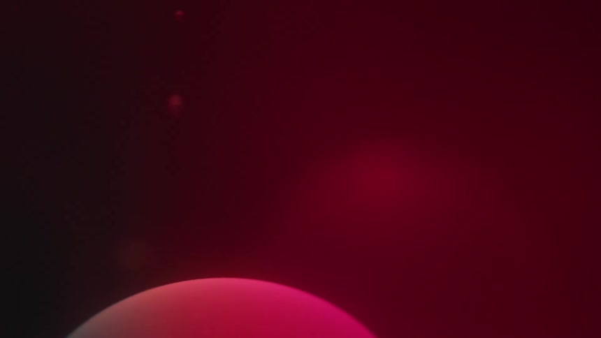 A blob with a gradient of red and green colors flows down a dark liquid
