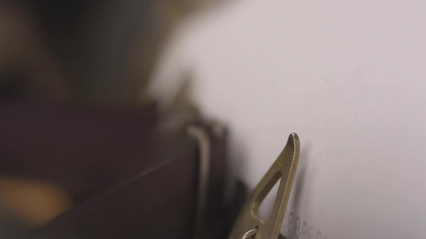 A typewriters platen with a sheet of paper partially inserted is seen in a closeup from a slight angle