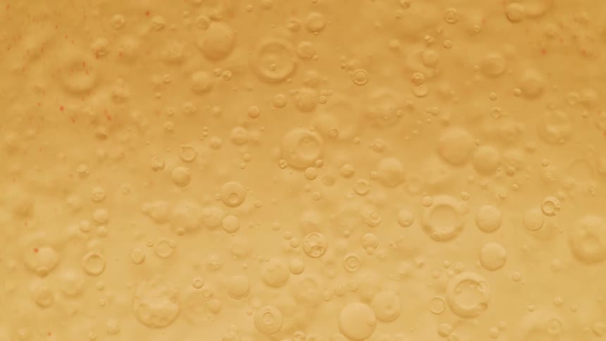 Bubbles of varying sizes are suspended in a translucent golden liquid