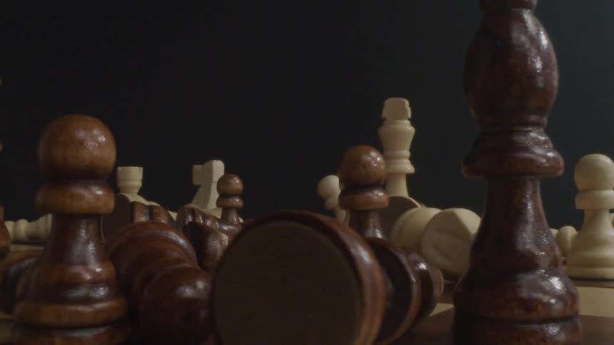 Chess pieces fall and scatter other arranged chess pieces on a chess board
