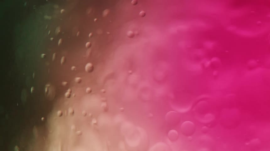 Abstract closeup of pink and brown fluid with floating bubbles