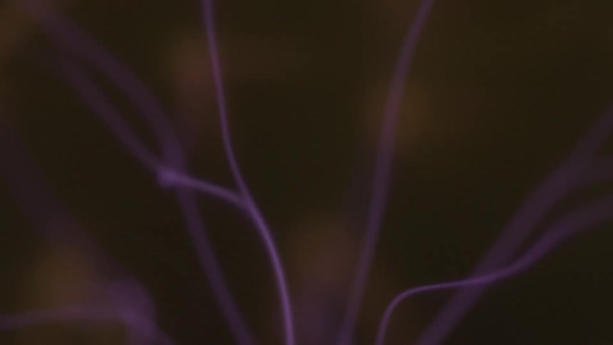 Bolts of electric purple plasma rays dance around in front of a blurred background