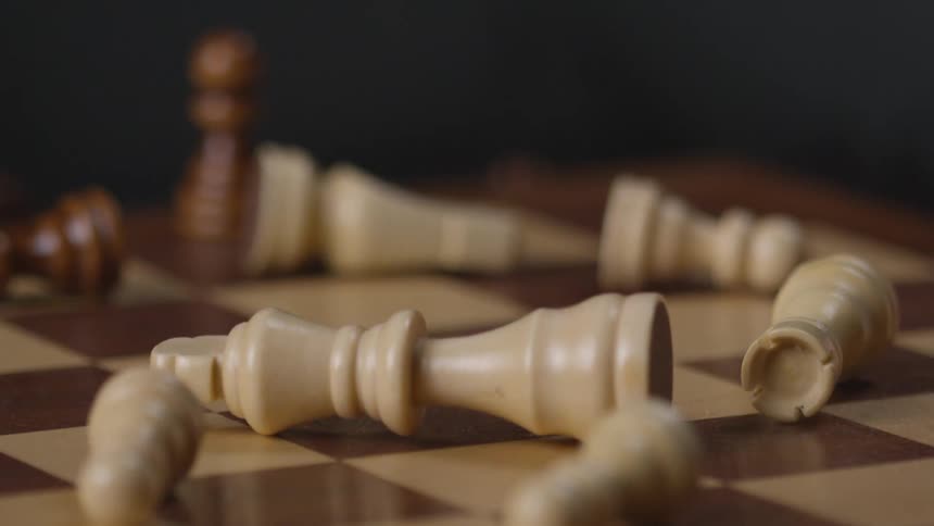 A chessboard has been bumped scattering the pieces across the board