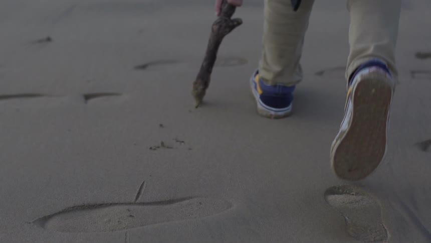 Boy traces in sand with a stick