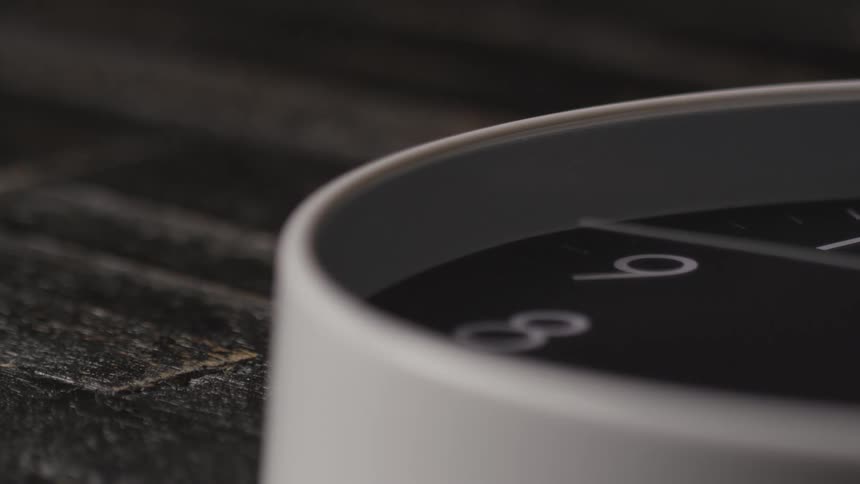 Close up of a ticking analog clock placed on a dark surface