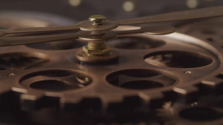 A closeup reveals the intricate brass gears and a central spindle of a clock mechanism