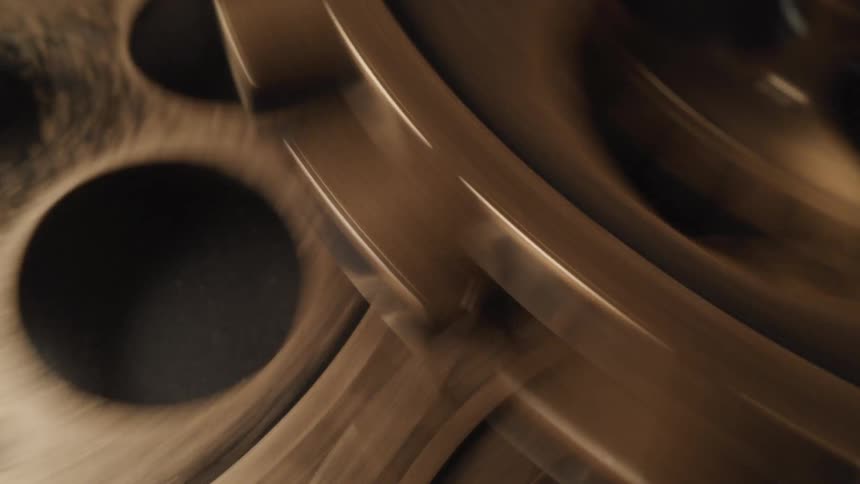 A detailed closeup shows the intricate dark brown circular patterns of interconnected gears spinning