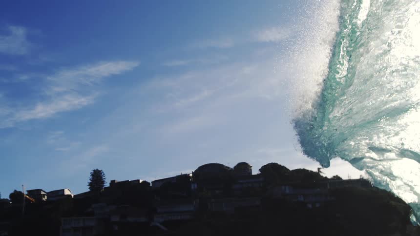 Crystal clear wave breaking in the ocean with the coast in the background