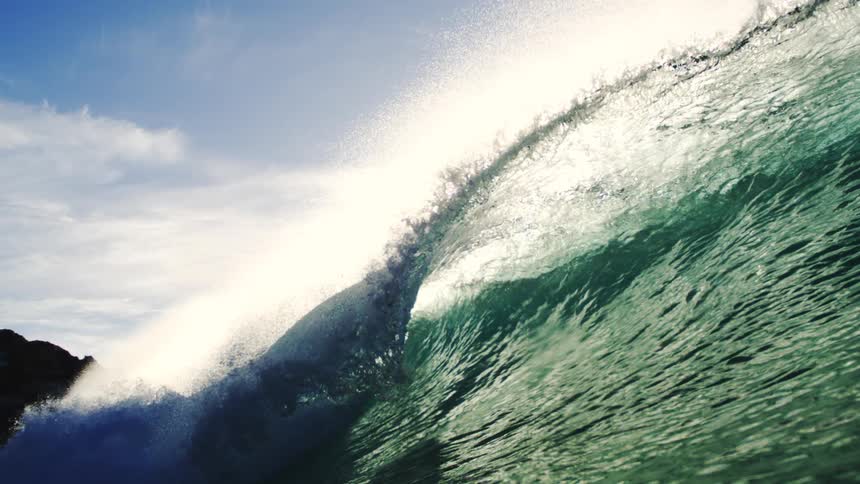 A big crystalclear wave under sunlight and a blue sky