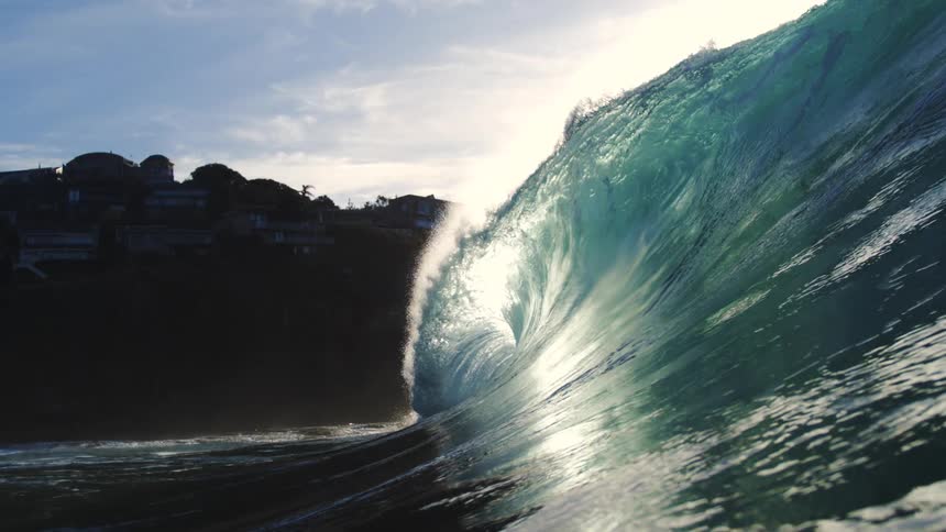 A large wave passes the homes on the cliff
