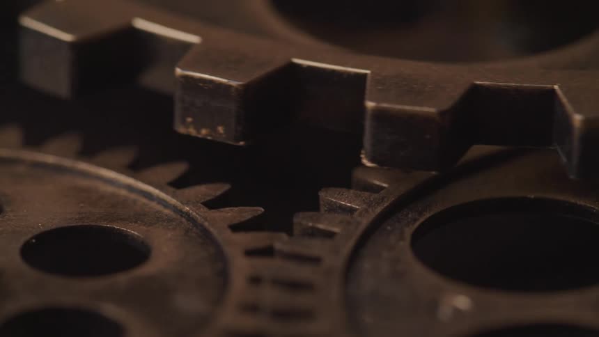 Antiqued bronze gears of a clock mechanism turning and interlocking teeth