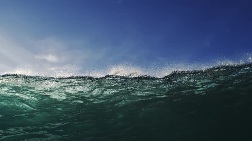Ocean waves forming and rising significantly creating a powerful swell under the bright midday sun