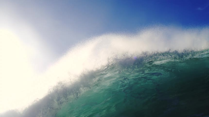 A big wave with crystalclear water and a blue sky
