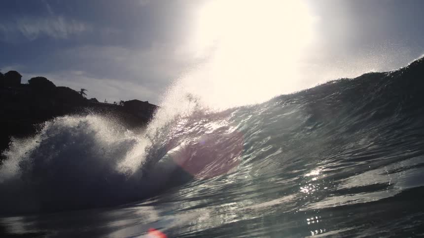The waves hit the shore by the homes on a mountain