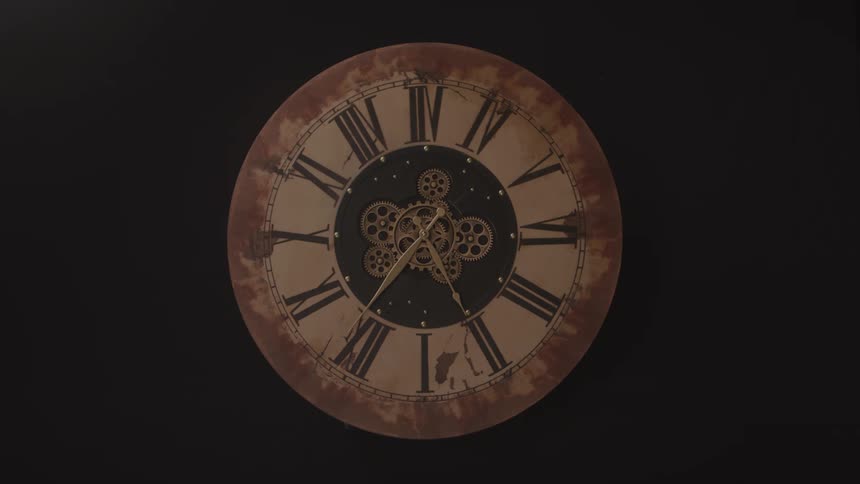 Gearsturn on the face of a clock in a dark area