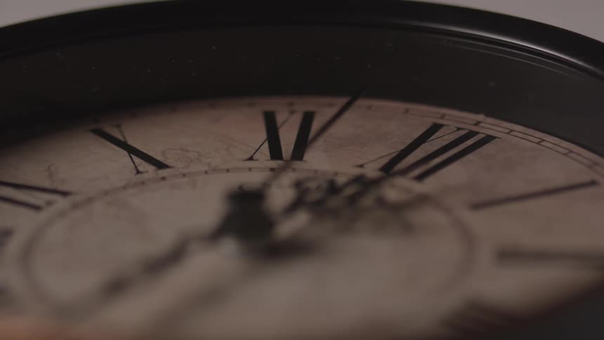 A closeup view of an antique clock face with roman numerals and ornate clock hands