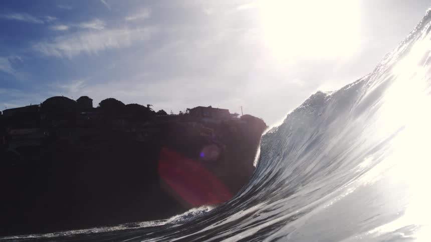 A big wave of crystalclear water with strong sunlight shining on it