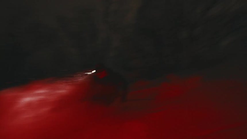 A skier speeds through a dark foggy area with a headlamp shining brightly with a red glow on the snowcovered ground