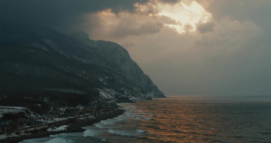 Aerial view of a snowy mountain on the ocean shore