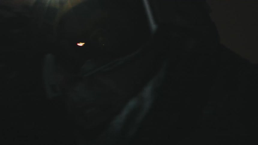 A man is snowboarding with a flashing headlight at night