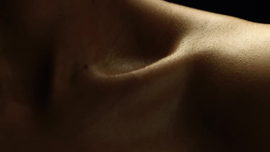 Closeup of a womans back and shoulder against a dark background