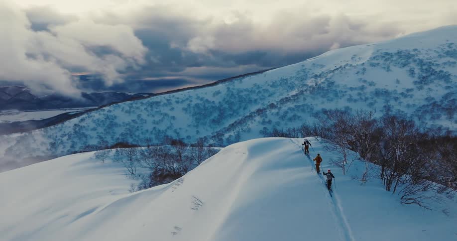 3 people on a trail over a snowcovered mountain