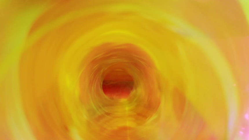 A dynamic abstract image features swirling bands of pink green and orange light emanating from a bright central yellow vortex