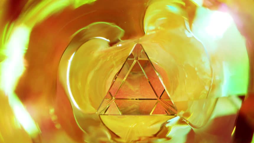 Close up of a glass triangle in an abstract orange reflection environment