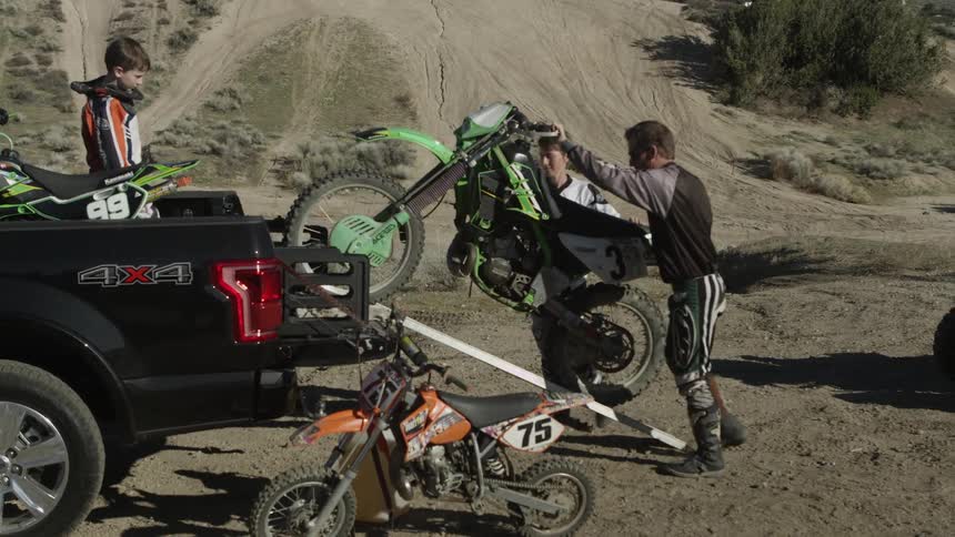 Guys unload a motorbike from the back of a truck