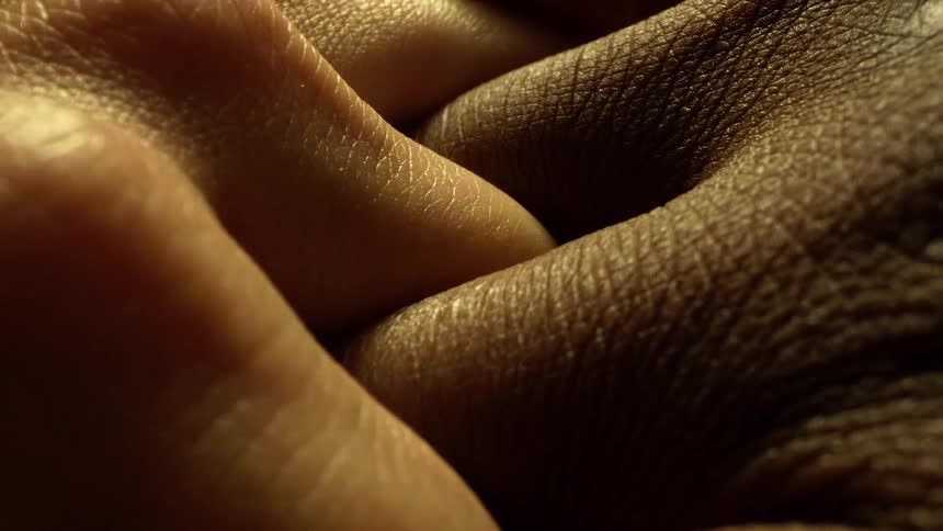 Closeup of two people intertwining their fingers