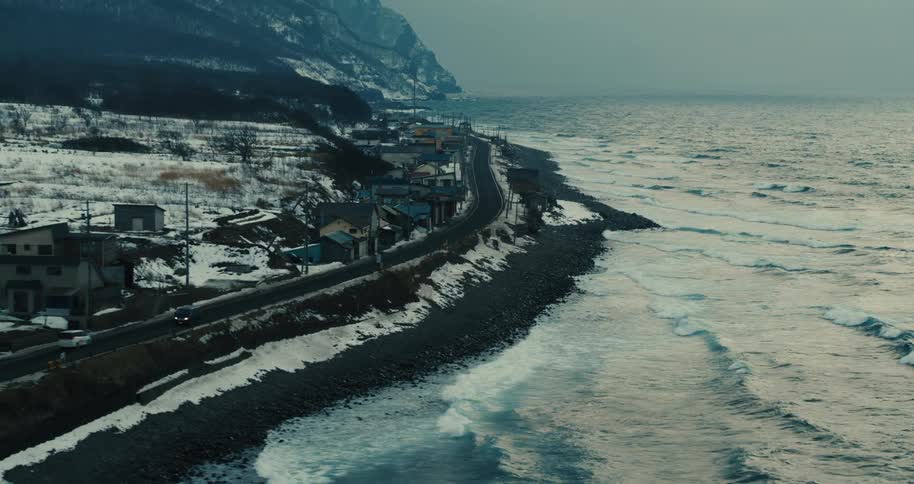 Aerial panorama of a small town at the foot of a snowy mountain and by the sea