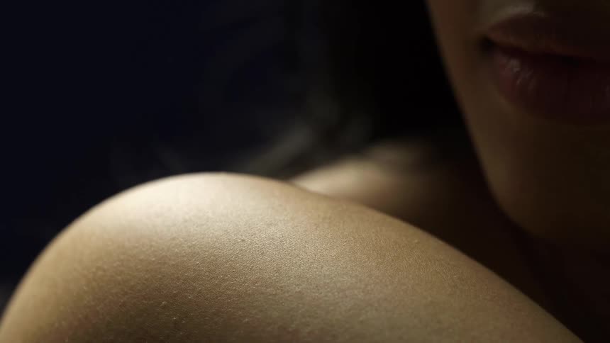 Close up of a female models shoulder and face area against dark background