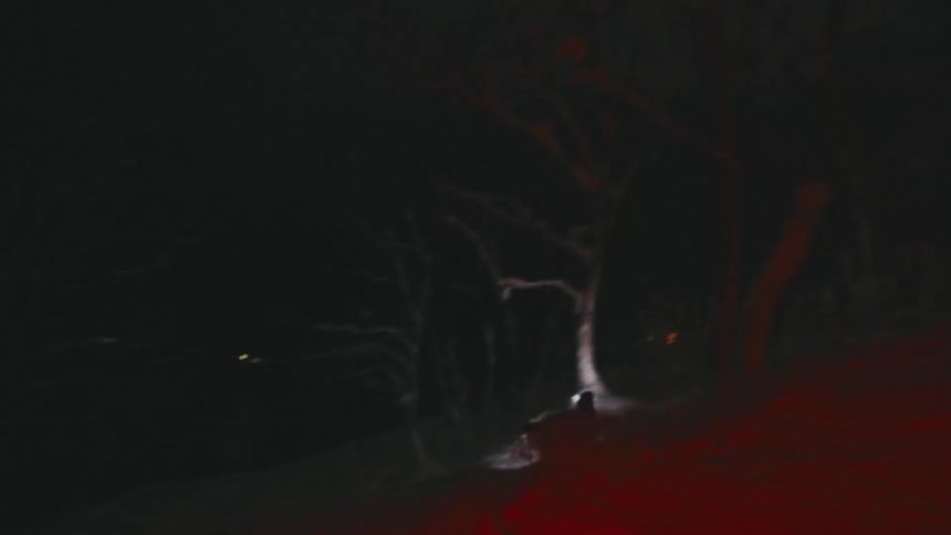 A snowboarder is heading downhill at night
