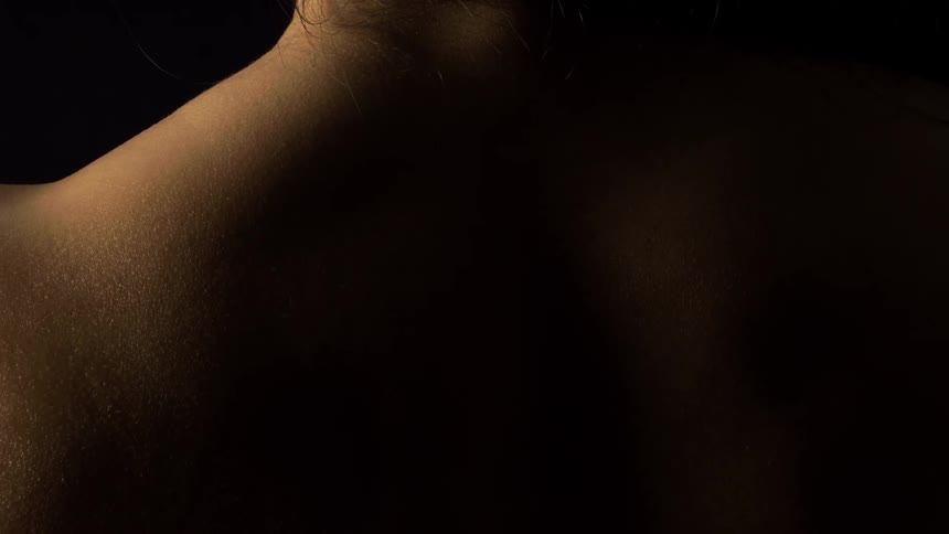 Close up of a womans skin as she flexes her back muscles