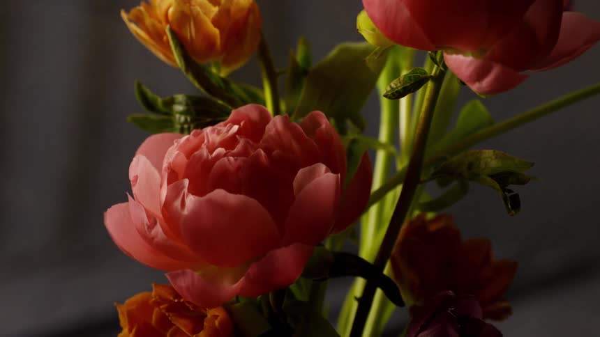 A thin cloud of smoke blows around behind a floral arrangement of pink and orange flowers