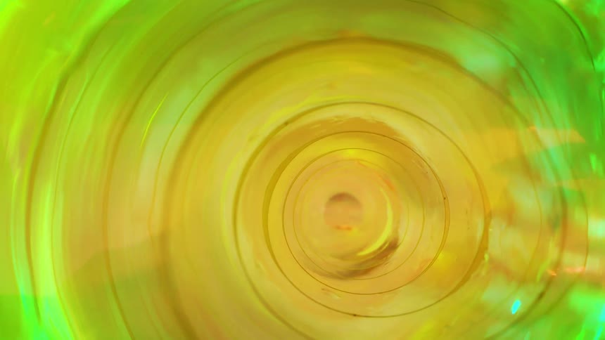 A vibrant abstract spiral of yellow and green tones viewed from the inside of a glass or plastic cylinder