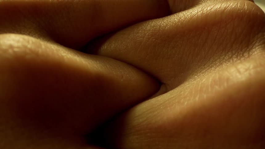 Close up of a persons hands with their fingers interlocked up to their knuckles