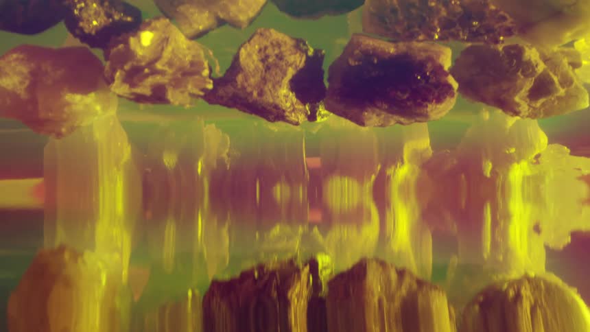 Rock crystals create smears and streaks in a reflective green fluid