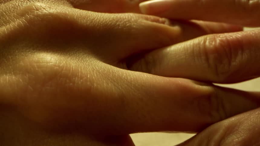 Close up of a persons hands as they separate their interlocked fingers