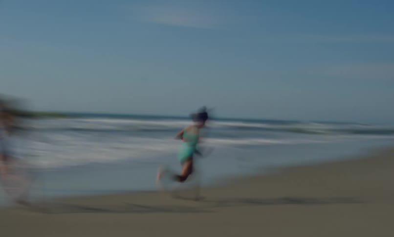 Fast forward motion of a young boy and two girls running and playing around on a beach on a sunny late afternoon.