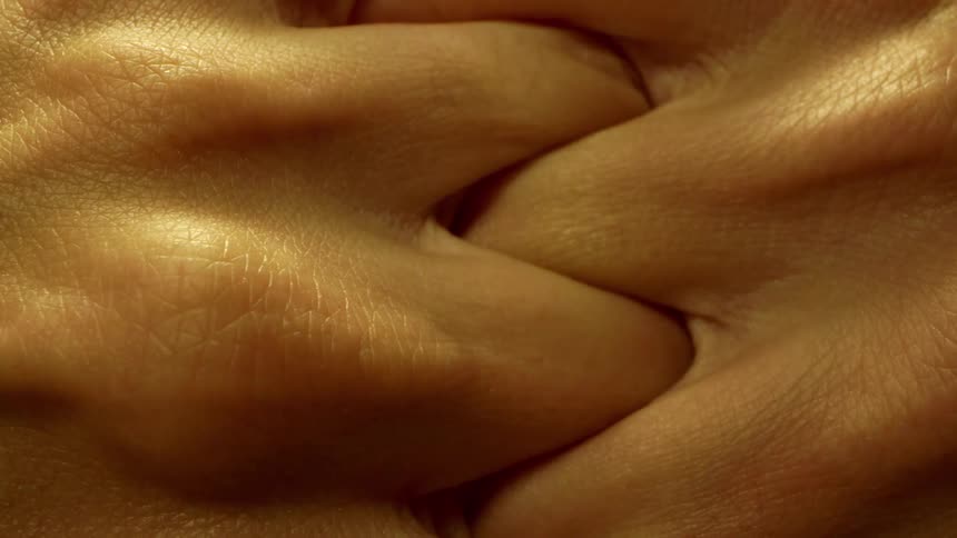 Two hands are intertwined closely together