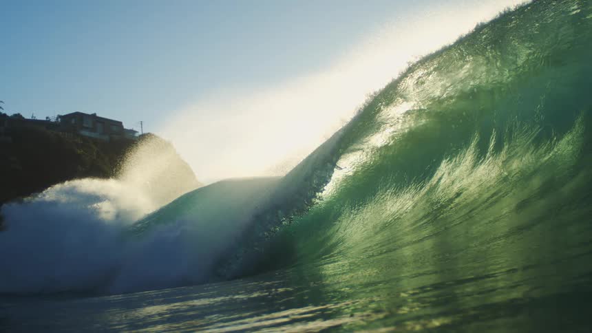 The large waves crashes by the cliff with homes on it