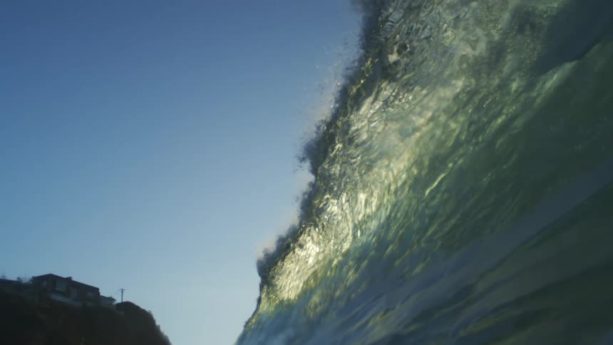 A large wave is falling by the shore