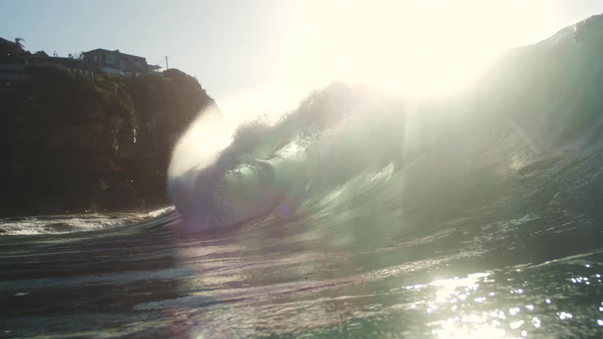 A large home is on the cliff as the wave reaches the shore