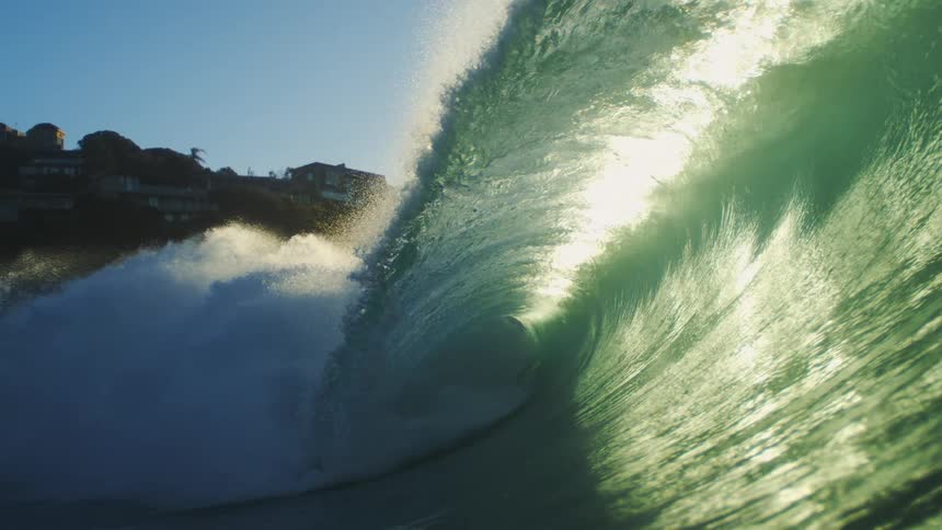 Homes are near the cliff where a huge wave is hitting the shore
