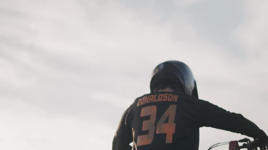Motocross rider in helmet and gear sits on a dirt bike looking back
