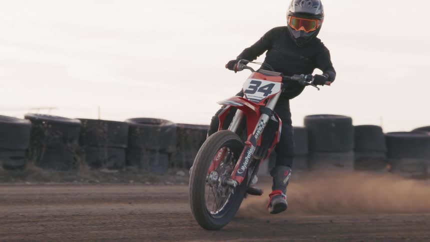 A man is speeding his dirt bike on the track
