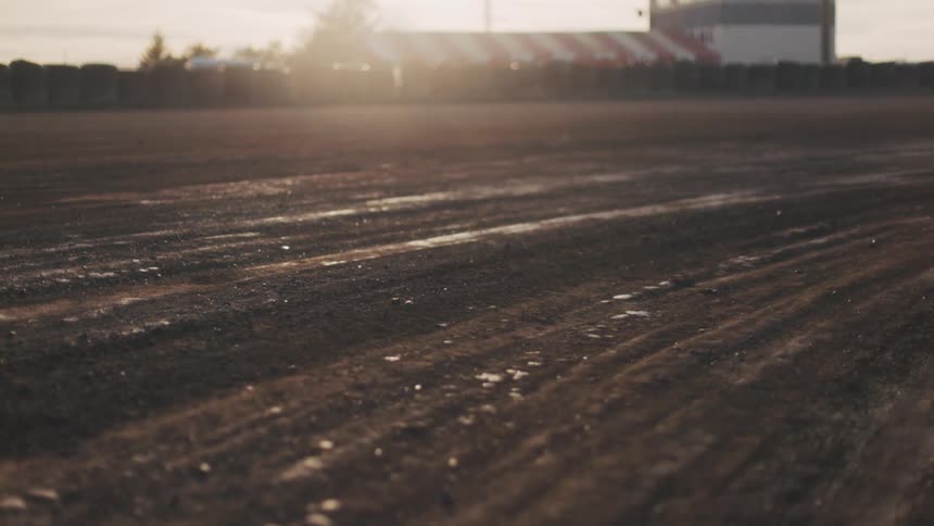 Dusty racetrack glows in warm sunrise light with a control tower in the distance